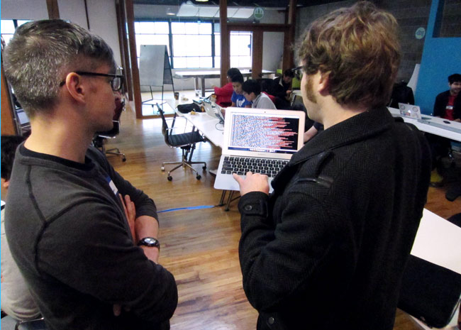 Kyle Drake shows the output of the NASDAQ API to a hackathon participant